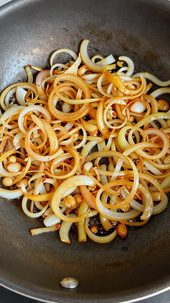 sizzling onions turning golden in heavy pan, overhead closeup